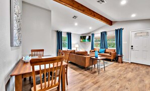 Cozy living area with a high ceiling, wooden dining table, and comfortable sofa.