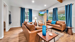 A modern living room with leather sofas, a coffee table, and a TV mounted on the wall. - Brazos River Bungalow - Close To Silos & Baylor (Waco)