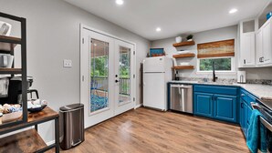 A modern kitchen with blue cabinets, stainless steel appliances, and a wooden floor. - Brazos River Bungalow - Close To Silos & Baylor (Waco)