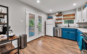 A modern kitchen with blue cabinets, stainless steel appliances, and a wooden floor.