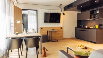 Eine moderne Küche mit Flachbildfernseher, Holzschränken und einem Essbereich mit Stühlen und Tisch.
