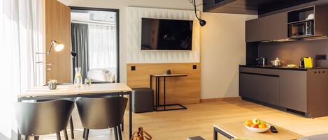 Una cocina moderna con un televisor de pantalla plana, armarios de madera y un comedor con sillas y una mesa.