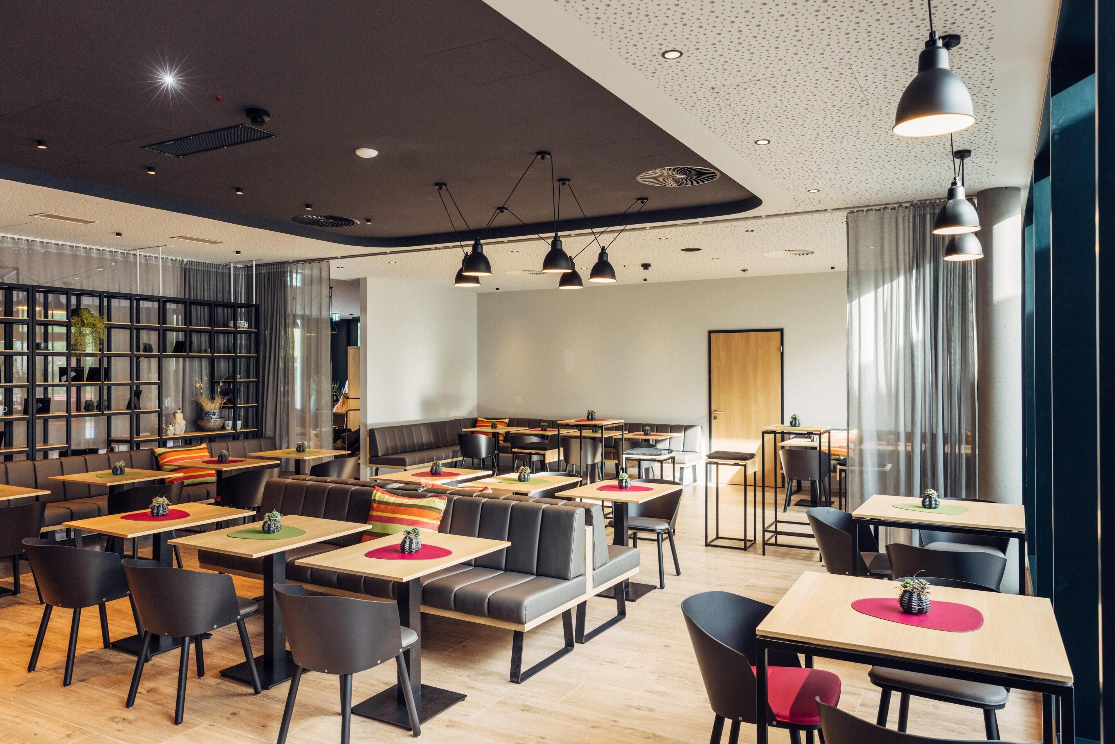 Un restaurante moderno con cabinas y mesas, iluminación colgante y una zona de bar.
