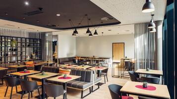 Un restaurante moderno con cabinas y mesas, iluminación colgante y una zona de bar.