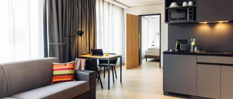 A modern living room with a sofa, dining table, and kitchen area.