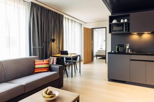 Una sala de estar moderna con sofá, mesa de comedor y zona de cocina.