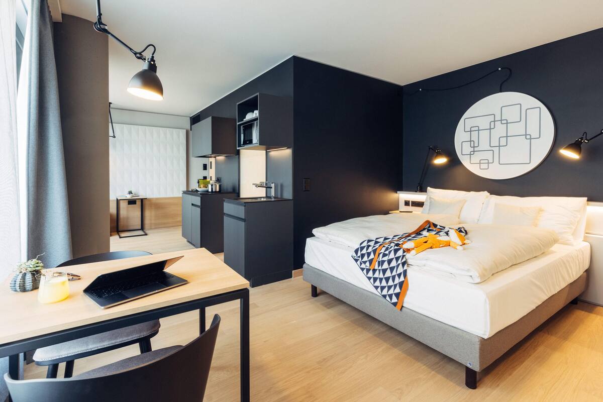 Une chambre d’hôtel moderne équipée d’un lit, d’un bureau et d’une kitchenette.