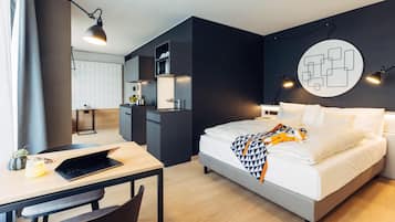 Une chambre d’hôtel moderne équipée d’un lit, d’un bureau et d’une kitchenette.