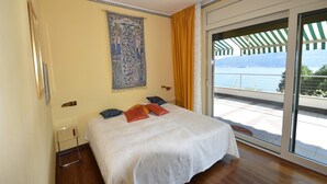 A bedroom with a bed, a large window, and a view of a body of water. - Apartment in Verbania near Lake and Islands (Verbania)