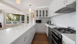 A modern kitchen with white cabinetry, a stainless steel stove, and a microwave.