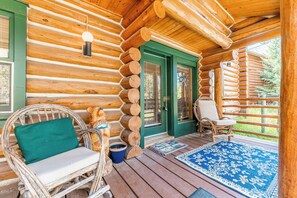 A log cabin with a porch, wicker chairs, a blue rug, and a wooden bench. - 88 Potentilla Lane by Summit County Mountain Retreats (Keystone)