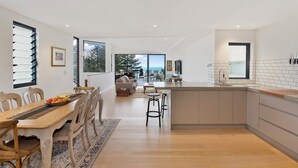 A modern kitchen with a dining area, large windows, and a view of the outdoors. - Magnificent 3BR Bronte Holiday House with Views (Bronte)