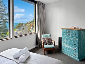Une chambre d’hôtel équipée d’un lit, d’une chaise, d’une commode et d’une grande fenêtre donnant sur la ville.