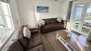 Una sala de estar con un sofá de cuero marrón, una mesa de centro de madera y un cuadro en la pared.