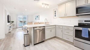 A modern kitchen with white cabinetry, stainless steel appliances, and a central island. - Premier Ocean View Corner Condo (850S.F.) (Plymouth)