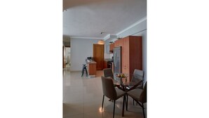 A modern kitchen with a central island, stainless steel appliances, and a dining area with a glass table and chairs.