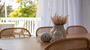 Ein Esstisch mit einer Vase getrockneter Blumen, einer Dekorationsschale und Korbstühlen.
