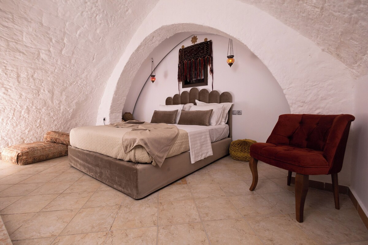 A bedroom with a bed, a chair, and a decorative wall.