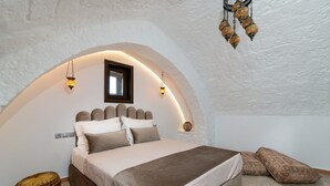 A bedroom with a vaulted ceiling, a bed with a headboard, bedside lamps, and a decorative hanging light fixture. - April Medieval Hotel (Rhodes)