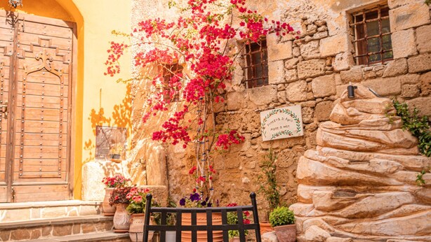 A table set with breakfast items, a stone wall, and a wooden door. - April Medieval Hotel (Rhodes)