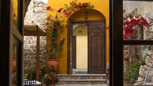 A courtyard with a stone wall, a wooden door, and potted plants. - April Medieval Hotel (Rhodes)