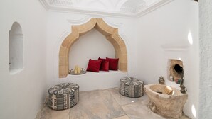 A traditional interior with a stone bench, a small alcove with a red cushion, and a stone basin. - April Medieval Hotel (Rhodes)