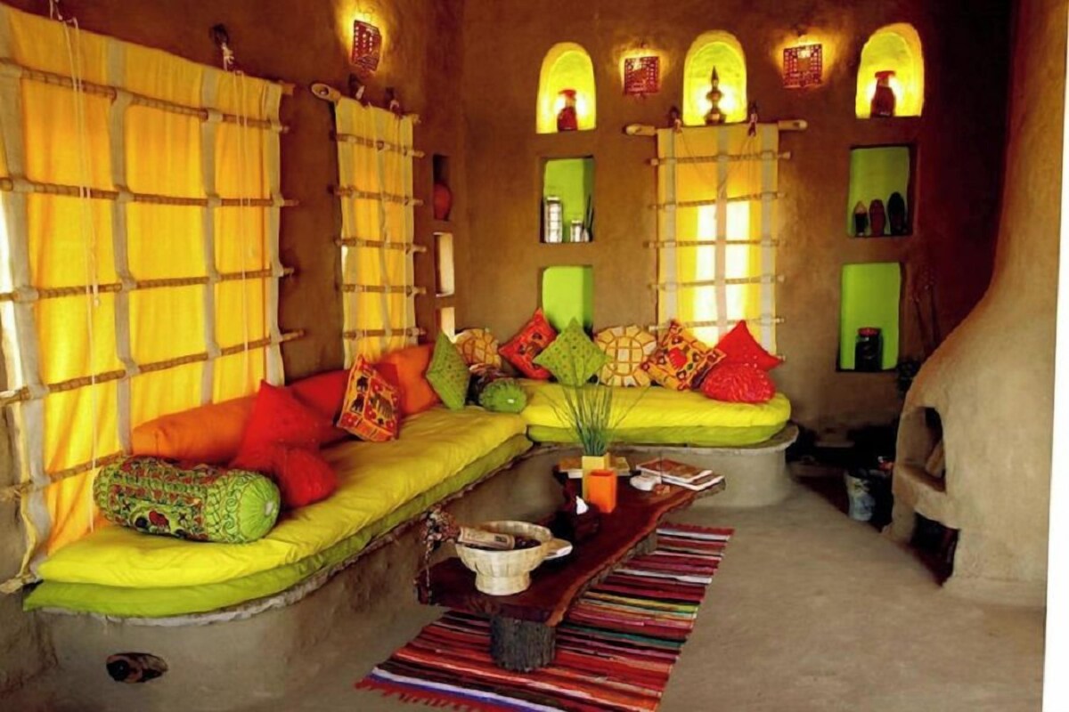 A cozy living room with a green sofa, colorful cushions, a small table, and a patterned rug.