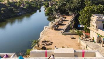 A balcony with colorful cushions overlooking a river and a traditional building.