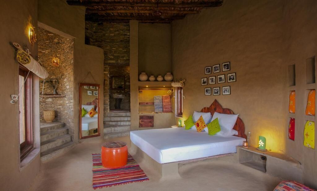 Un dormitorio con una cama, una mesita pequeña, un taburete y una escalera que lleva a un nivel superior.