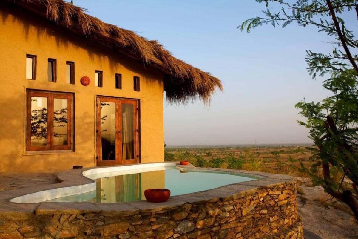 A building with a thatched roof, a swimming pool, and a view of the landscape.
