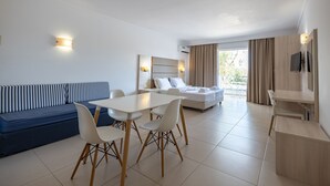 Un salon moderne comprenant un coin repas, un canapé et un téléviseur fixé au mur.