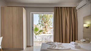 Une chambre d’hôtel équipée d’un lit, d’un bureau, d’une chaise, d’une table et offrant une vue sur l’extérieur.