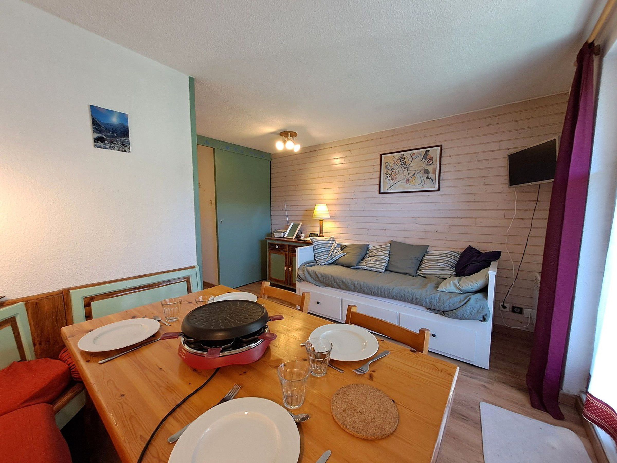 A compact living space with a dining area, a kitchenette, a sofa, and a television.
