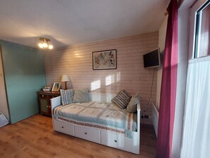 A bedroom with a bed, bedside table, lamp, and a painting on the wall.