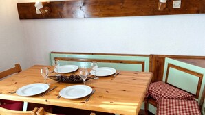 Ein Essbereich mit einem Holztisch, gedeckt für vier Personen, umgeben von Holzstühlen mit roten Kissen.