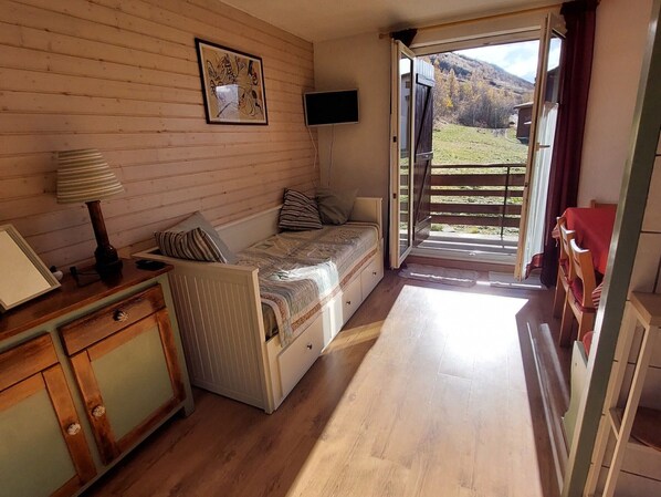 A cozy room with a bed, a desk, a TV, and a window with a view of the outdoors.