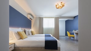 A modern hotel room with a large bed, a desk, and a chair. - Antoniel Suites (St. Julian's)