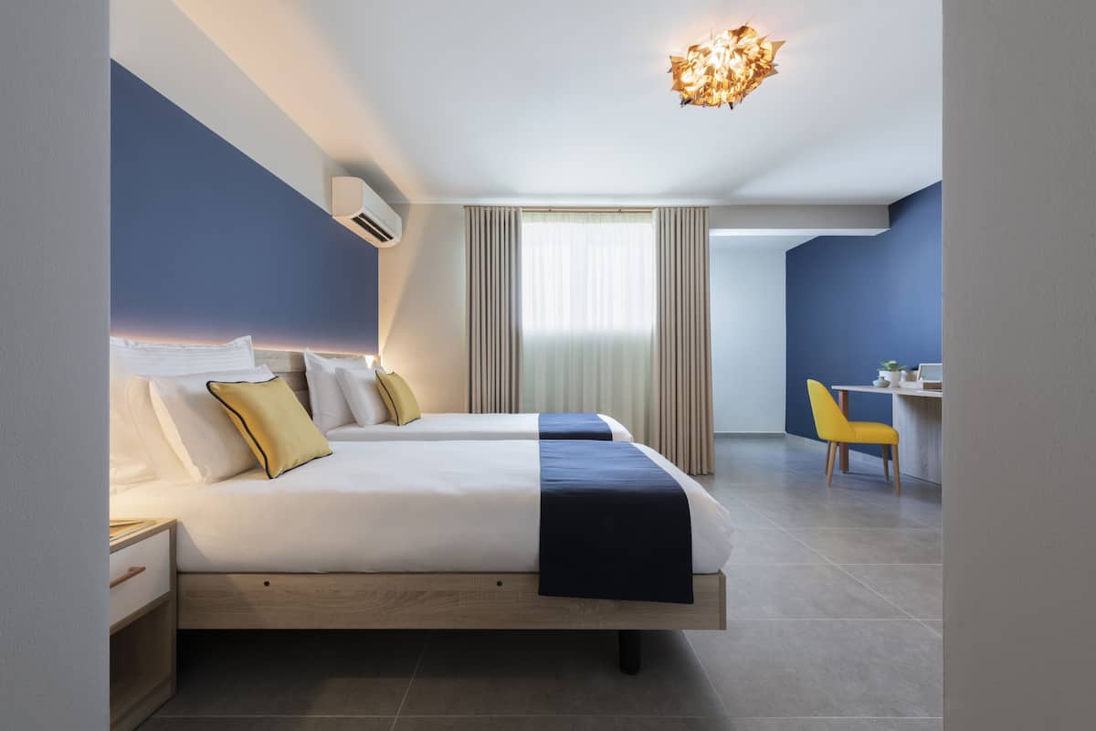 A modern hotel room with a large bed, a desk, and a chair.
