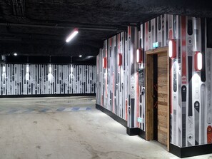 A spacious indoor area with a concrete floor and walls adorned with vertical stripes of skis and snowboards.