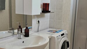 Ein modernes Badezimmer mit Waschbecken, Spiegel, Schrank und Waschmaschine.