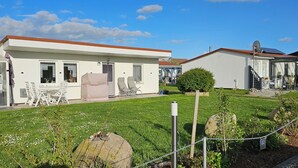 Eine Reihe von weißen Mobilheimen mit Anbauten und Terrassen, einem Rasen und einem kleinen Gartenbereich.