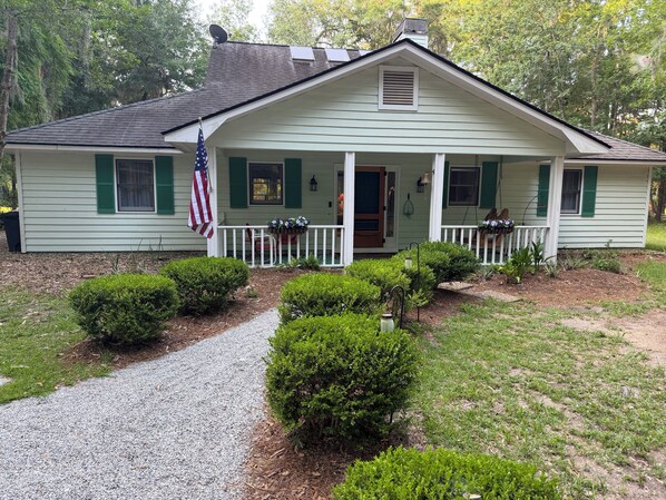 A single-story house with a front porch, a gravel driveway, and a small garden.