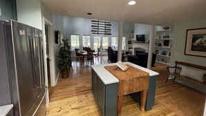 A spacious kitchen with wooden flooring, a built-in refrigerator, and a dining area with a table and chairs. - Single Family Home, Land trans Round Trip! Melrose Pool Open! (Daufuskie Island)