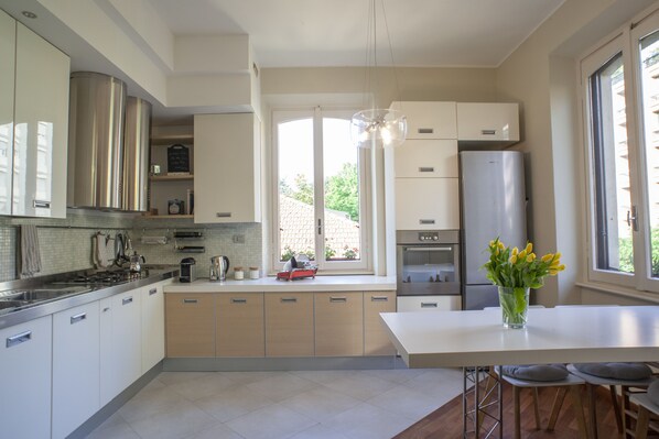 A modern kitchen with stainless steel appliances, a central island, and a view of the outdoors.