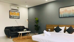Une chambre d’hôtel moderne avec un grand lit, un canapé, une petite table ronde et une plante en pot.