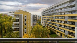 Ein mehrstöckiges Wohngebäude mit Balkonen, einem zentralen Innenhof und umliegender Bepflanzung.