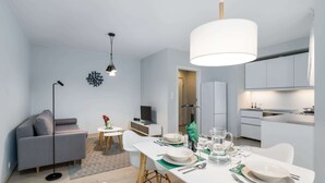 Eine moderne Wohnung mit Essbereich, Küchenzeile und einem grauen Sofa.