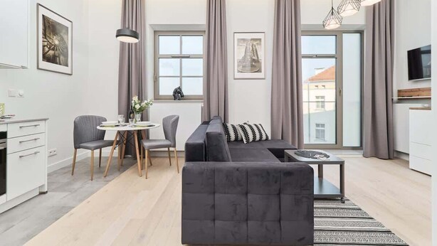Ein modernes Wohnzimmer mit einer Couch, einem Esstisch, Stühlen und Kunstwerken an den Wänden.