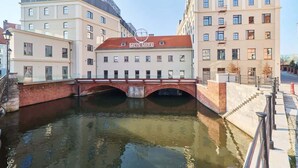 Ein Gebäude mit der Aufschrift 'MEYN-MARIA' an der Vorderseite, eine rote Brücke über einem Kanal und moderne Architektur.