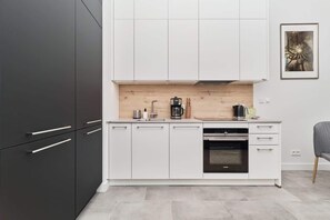 A modern kitchen with white cabinets, a wooden countertop, and a built-in oven. - Comfortable Studio | Balcony with River View (Wroclaw)